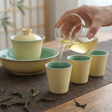Pouring tea from a glass fair cup into gongfu tea cups