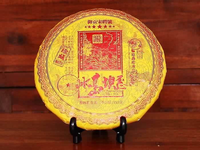 Yellow tea cake on a black stand against a wooden background