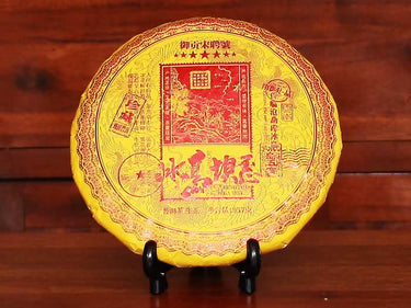 Yellow tea cake on a black stand against a wooden background